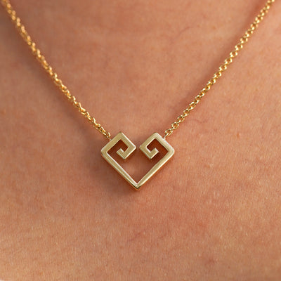 A close up view of a model's neck wearing a yellow gold Large Chere Heart Necklace