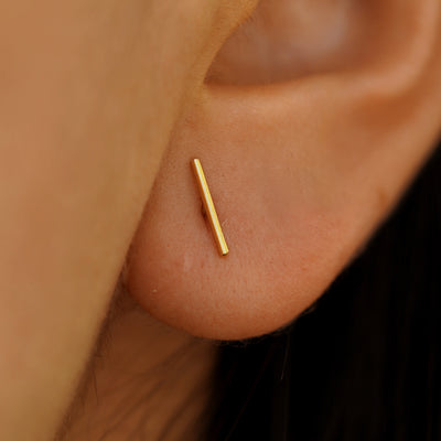 Close up view of a model's ear wearing a Large line Earring in Yellow Gold.