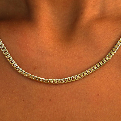 Close up view of a model's neck wearing a solid 14k yellow gold Medium Miami Chain
