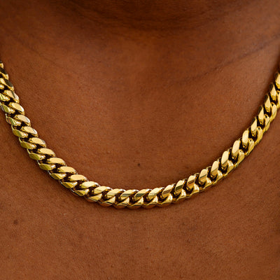 Close up view of a model's neck wearing a yellow gold Miami Cuban Chain