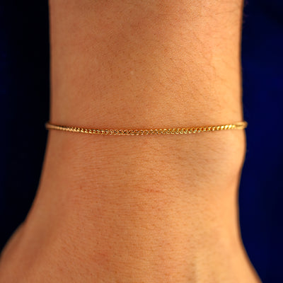 Close up view of a models wrist wearing a solid 14k yellow gold Mini Franco Chain Bracelet