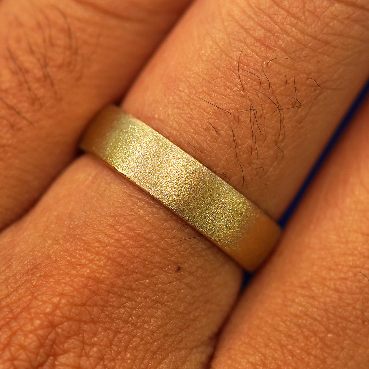 Close up view of a model's fingers wearing a 14k yellow gold Mix Stardust Band