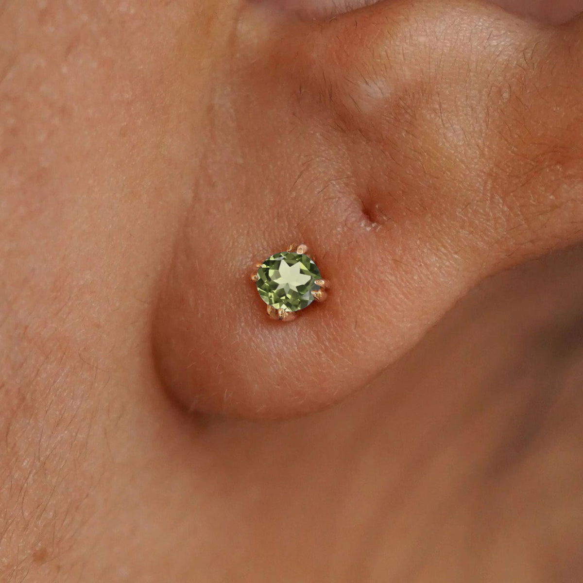 Close up view of a model's ear wearing a 14k yellow gold Peridot Earring