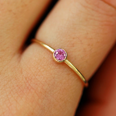 Close up view of a model's fingers wearing a 14k yellow gold Pink Sapphire Ring