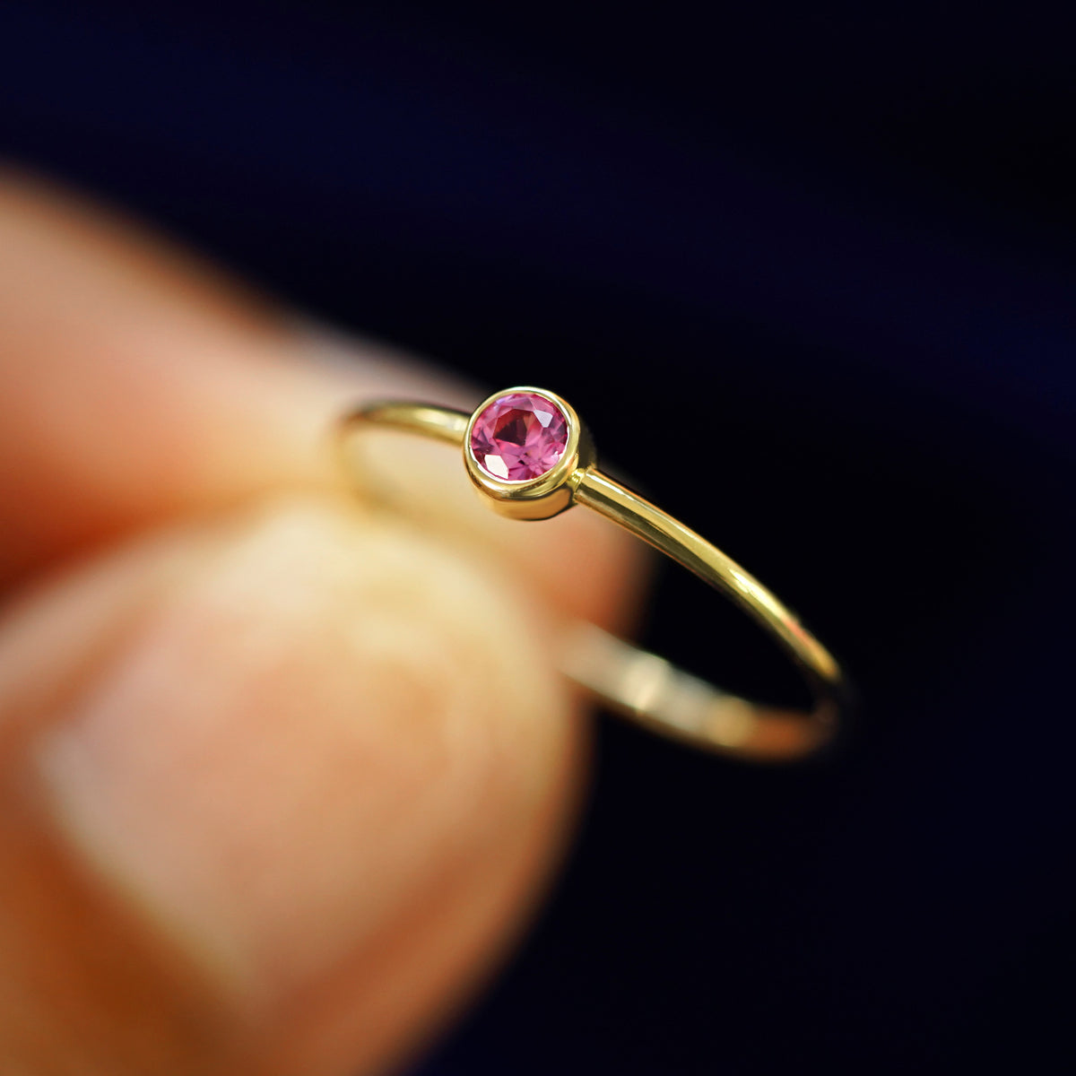 A model holding a Pink Sapphire Ring tilted to show the bezel setting