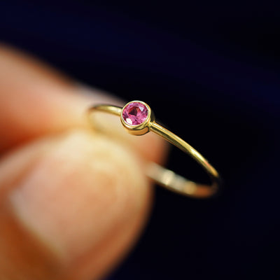 A model holding a Pink Sapphire Ring tilted to show the bezel setting