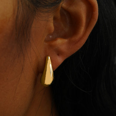 A model's ear wearing a solid yellow gold Teardrop Puffy Earring