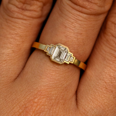 Close up view of a model's hand wearing a 14k yellow gold Emerald Cut and Baguette Diamond Ring