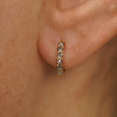 Close up view of a model's ear wearing a yellow gold Small Salt and Pepper Diamond Huggie Hoop