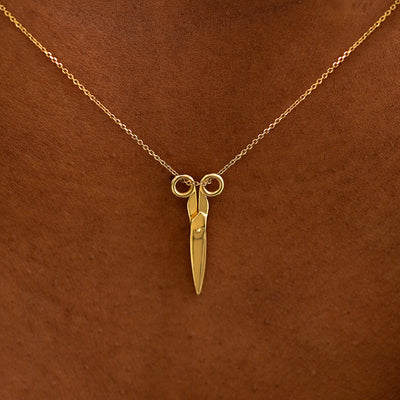 Close up view of a model's neck wearing a solid 14k yellow gold Scissors Necklace