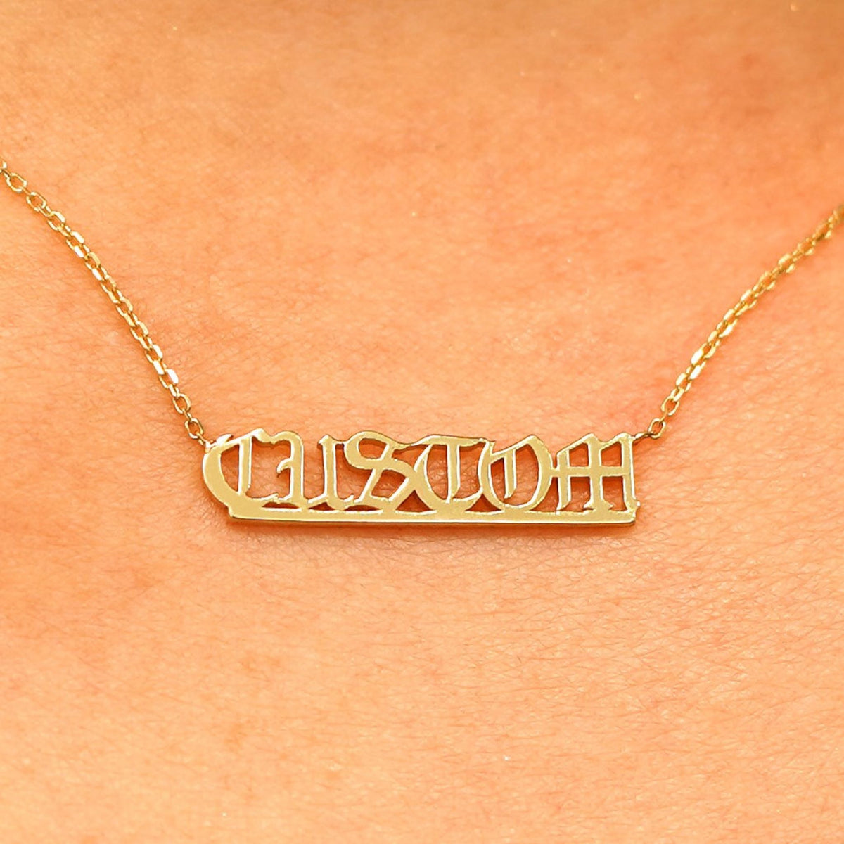 Close up view of a model's neck wearing a yellow gold Small Custom Nameplate necklace that says Custom