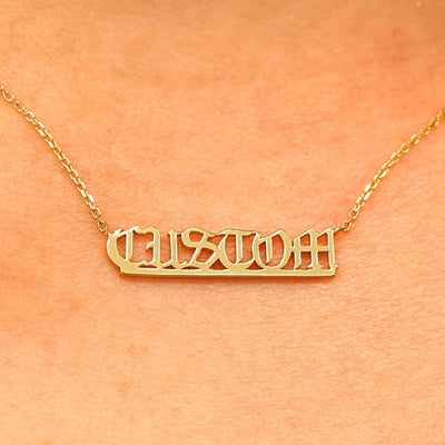 Close up view of a model's neck wearing a yellow gold Small Custom Nameplate necklace that says Custom