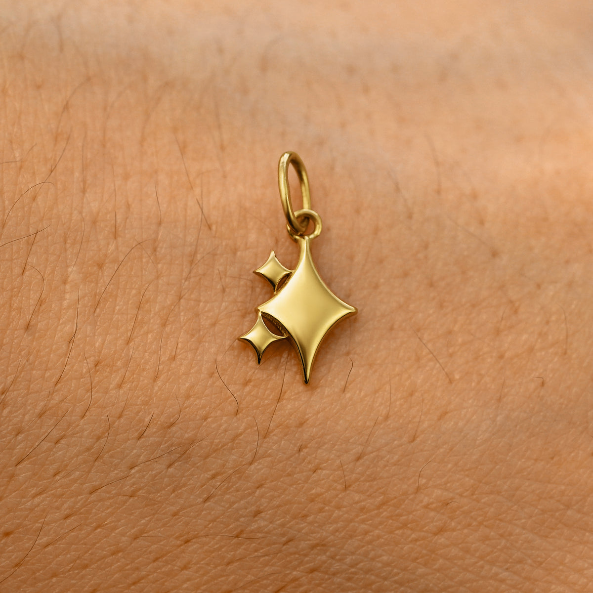 A solid 14k yellow gold Sparkly Emoji Charm resting on the back of a model's hand