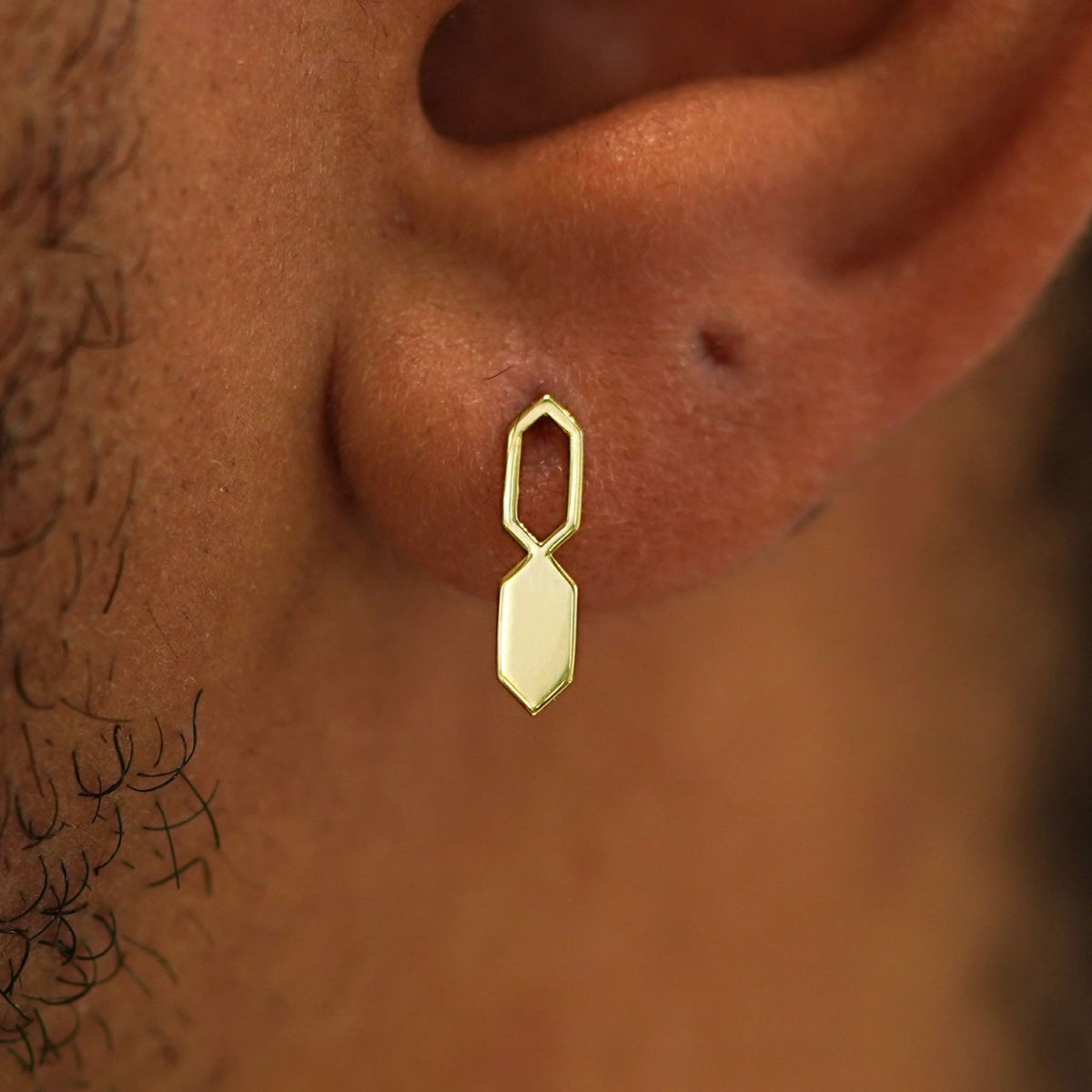 Close up view of a model's ear wearing a 14k gold Tanlah Earring vertically