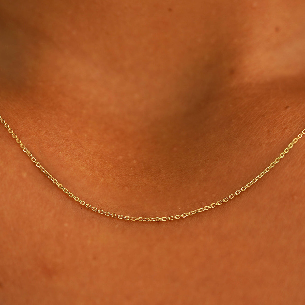 Close up view of a model's neck wearing a 14k yellow gold Cable Chain