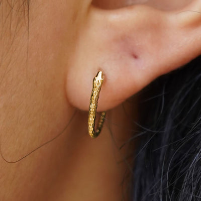 Close up view of a model's ear wearing a yellow gold Snake Hoop / Piercing