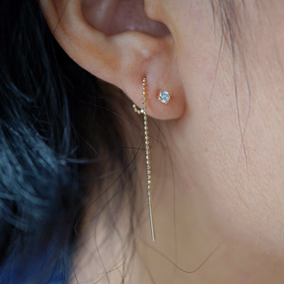 Close up view of a model's ear wearing an aquamarine Gemstone Threader through two piercings