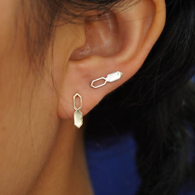 Close up view of a model's ear wearing two yellow gold Tanlah Earrings in two separate lobe piercings