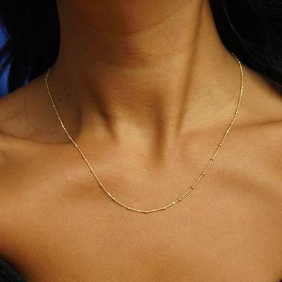 Close up view of a model's neck wearing a yellow gold Beads Chain