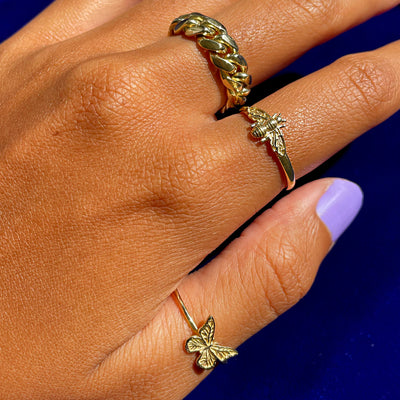 Close up view of a model's hand wearing a Miami Cuban Ring, a Curvy Bee Ring, and a Butterfly Ring