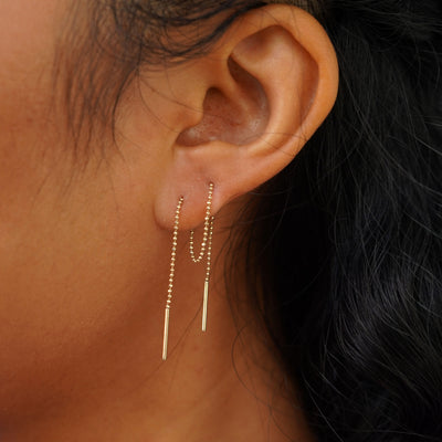 A model's ear wearing a Threader through looped tightly in the front through two piercings and dangling