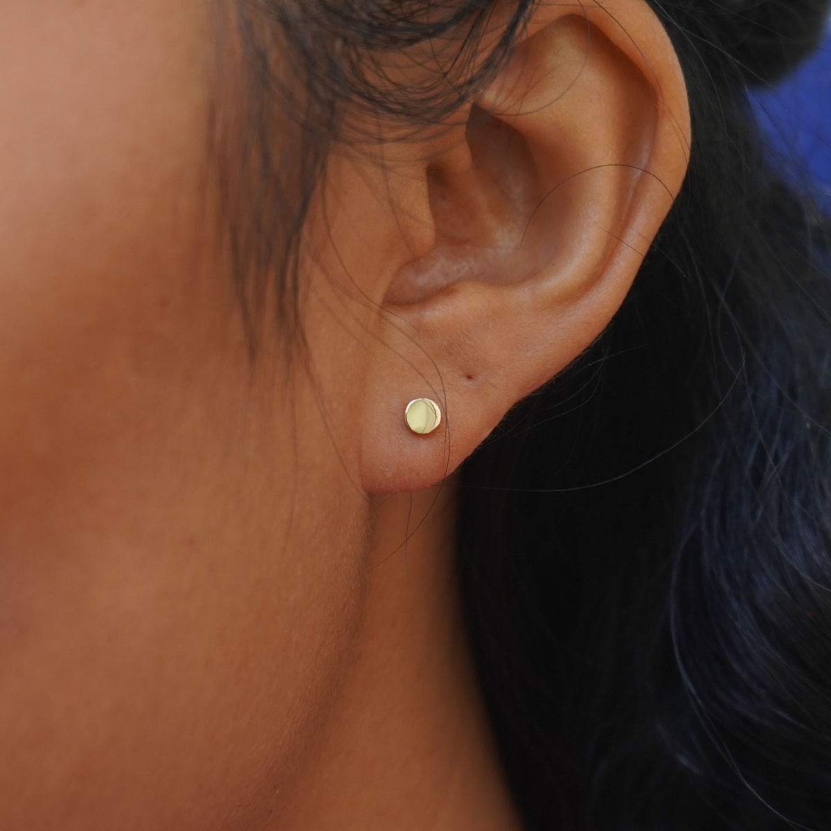Close up view of a model's ear wearing a yellow gold Large Flat Back Earring