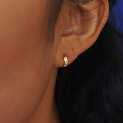 Close up view of a model's ear wearing a yellow gold Mini Thick Huggie Hoop
