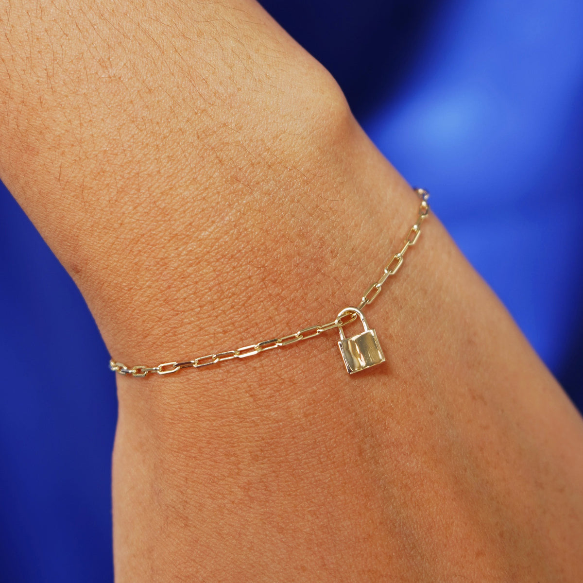 Close up view of a model's wrist wearing a yellow gold Lock Charm on a Butch Bracelet