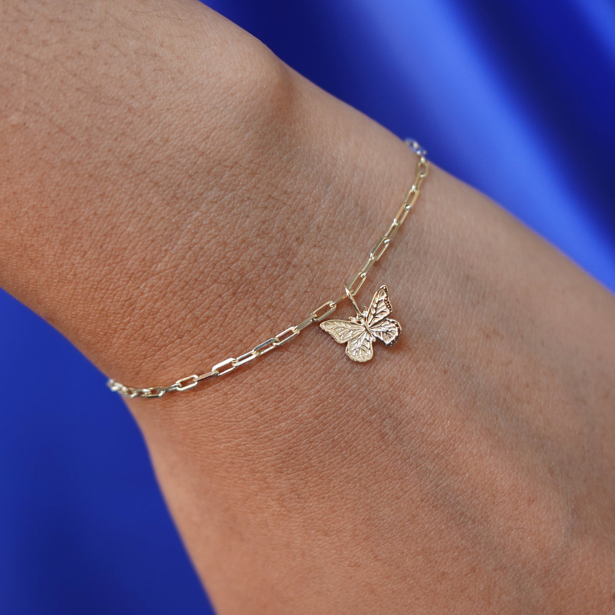 Close up view of a model's wrist wearing a yellow gold Butterfly Charm on a Butch Chain Bracelet