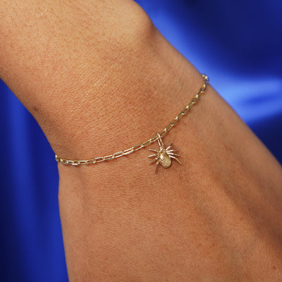 Close up view of a model's wrist wearing a yellow gold Spider Charm on a Butch Chain Bracelet